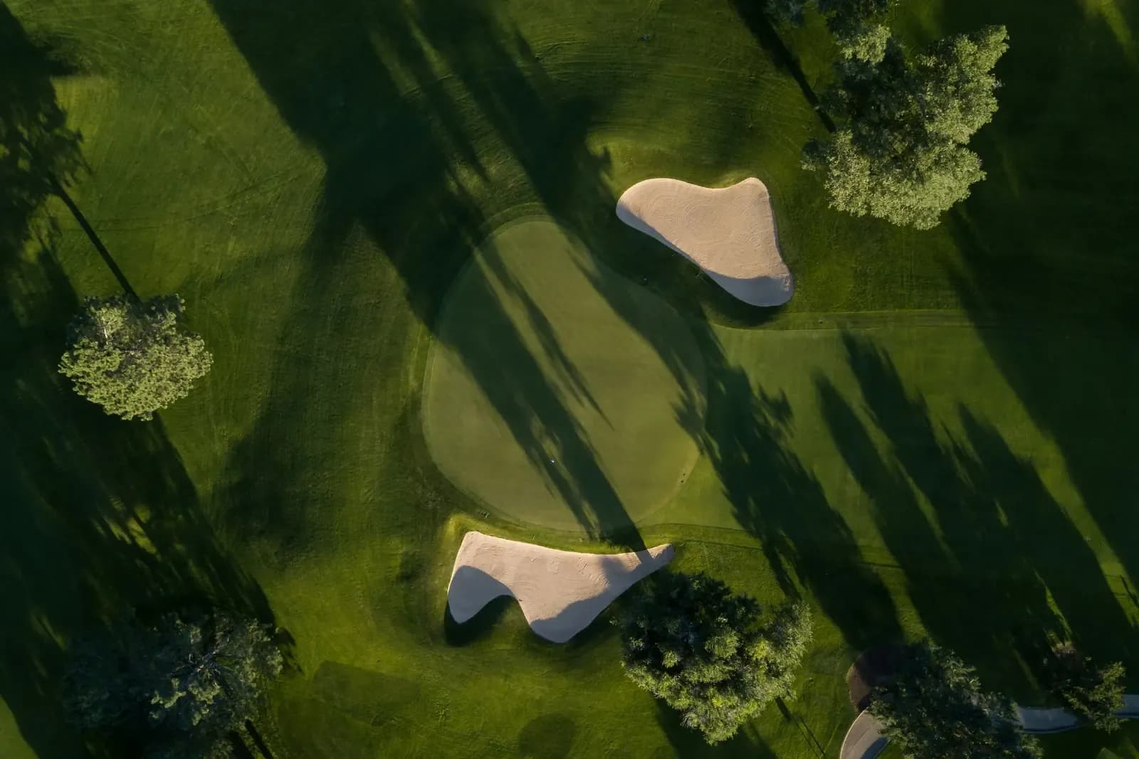 Aerial view of golf course sand bunkers surrounded by lush green fairways and mature trees