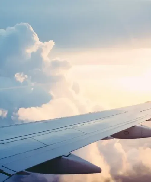 Aircraft wing against golden sunset clouds during flight, showcasing seamless travel to luxury holiday destinations