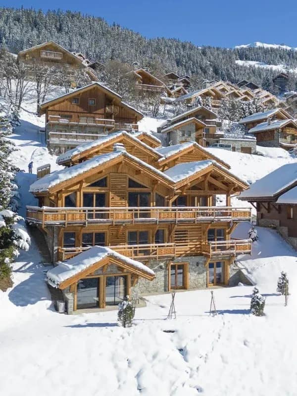 Luxury wooden chalets nestled in snowy Alpine village with traditional timber architecture and mountain views
