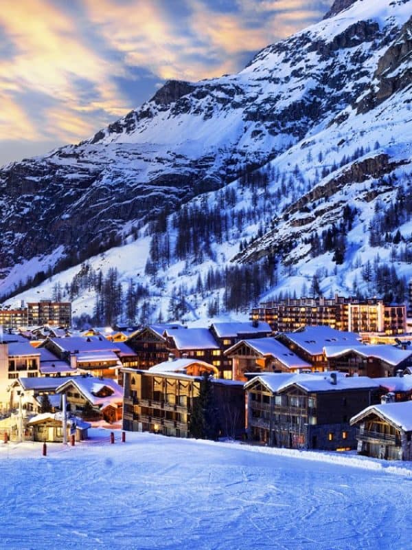 Snow-covered alpine village at dusk with luxury chalets and ski slopes in Val d'Isère, French Alps